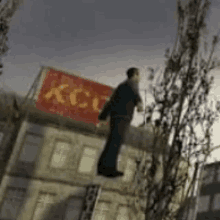 a man is flying through the air in front of a building with a sign that says kcc .