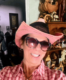 a woman wearing a pink cowboy hat and sunglasses smiles