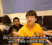 a man in a yellow shirt is talking about a big cheese roll