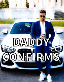 a man in a suit sits in front of a white car with the words " daddy confirms "