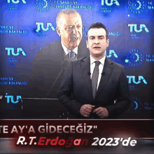 a man in a suit stands in front of a sign that says r.t. erdogan 2023