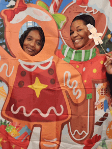 two women are standing in front of a gingerbread man