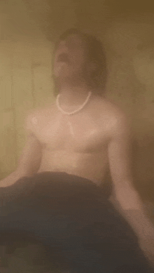 a shirtless man is sitting in a sauna with his eyes closed and his mouth open .