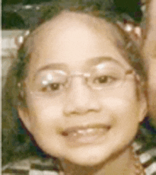 a young girl wearing glasses and a headband is smiling for the camera .