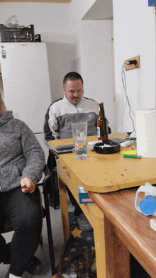 a man sits at a table with a bottle of beer on it