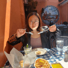 a woman is sitting at a table with a plate of food in front of her