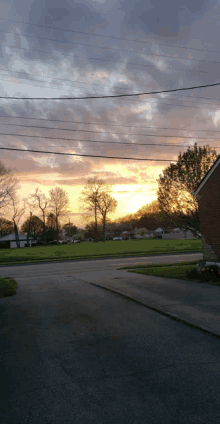 a sunset over a neighborhood with a brick house in the foreground