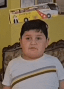 a young boy is sitting on a couch in front of a toy bus on the wall .