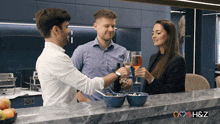 a man and two women are toasting with wine glasses in front of a counter that says h & z