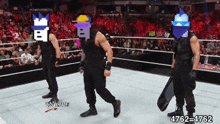 three men are standing in a wrestling ring with their faces covered in pixel art .