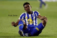 a soccer player wearing a blue and white striped shirt with a yellow a on the front sits on the ground