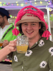 a man wearing a hat that says tech on it is holding a beer