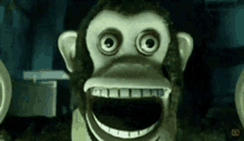 a stuffed monkey with a big smile on its face is standing in a dark room .