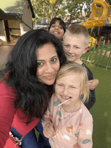 a woman is posing for a picture with three children