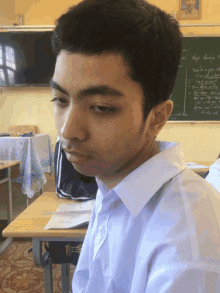 a young man sits at a desk in front of a chalkboard that says lap