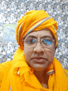 a man wearing glasses and a yellow turban poses for a photo