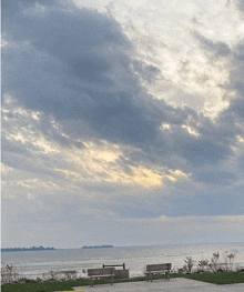 a couple of benches sit on a sidewalk overlooking the ocean