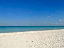 a beach with a blue sky and a sailboat in the distance