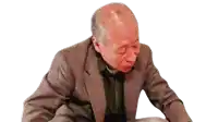 an elderly man in a suit is sitting down with his eyes closed