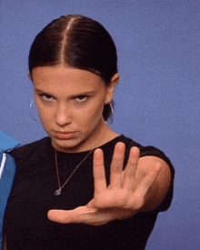 a woman in a black shirt is making a stop sign