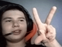 a young man wearing headphones is making a peace sign .