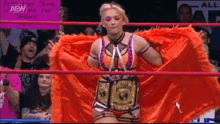 a woman is standing in a wrestling ring wearing an orange cape