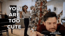 a man and a woman are decorating a christmas tree in a living room while a woman looks on .