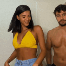 a woman in a yellow bikini top stands next to a man