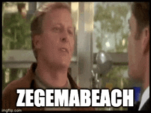 a man is talking to another man in front of a window and the words zegema beach are written on the screen .