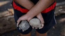 a man is holding two rocks in his hands with his arms crossed .