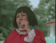 a woman in a red dress and wig is eating a candy bar .