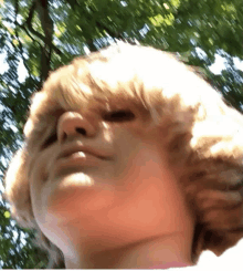 a close up of a child 's face with trees behind him