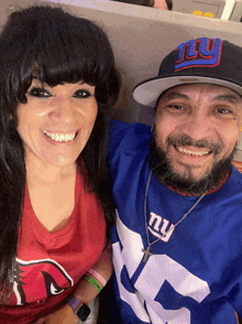 a man wearing a new york giants jersey stands next to a woman wearing a red shirt