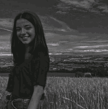 a black and white photo of a girl standing in a field