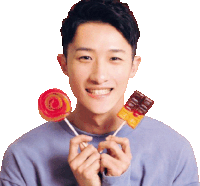 a man in a blue shirt is holding a lollipop and a chocolate bar