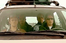 three people are sitting in a car with a roof rack on top of them