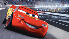 lightning mcqueen from the movie cars is smiling while driving on a race track