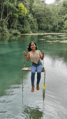 a woman sits on a swing over a lake