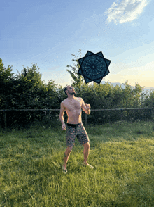 a shirtless man is playing frisbee in a field with a mandala in the background