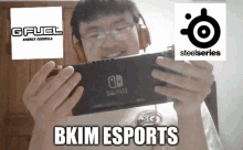 a man wearing headphones is holding a nintendo switch next to a gfuel and steelseries logo .