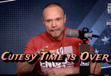 a man in a red shirt is sitting in front of a microphone with the words cutesy time is over above him