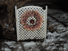 a white lattice fence with a pink wreath on top of it