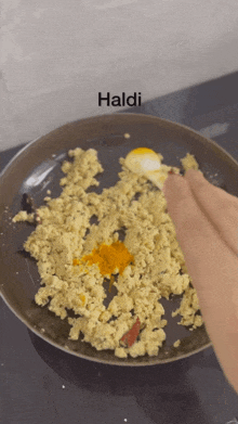 a person is stirring food in a frying pan and the word haldi is on the bottom