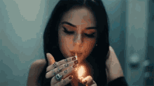 a young woman is lighting a cigarette with a lighter .