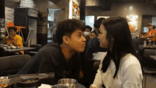 a man and a woman are looking at each other in a restaurant with a vending machine in the background