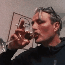 a man is drinking a glass of wine from a glass .