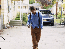 a man in a blue shirt and brown pants is walking in front of a car with a license plate that says n.j.