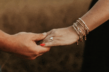 a woman with red nail polish is holding another woman 's hand with an engagement ring on her finger