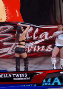 a woman is dancing in front of a sign that says bella twins on it