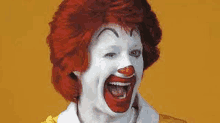 a close up of a mcdonald 's clown with red hair and white face paint .